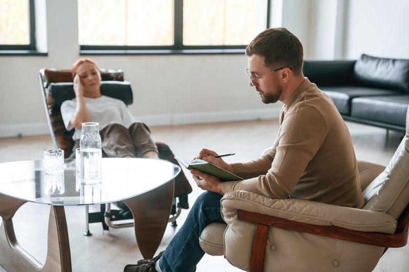 woman with head in hand talking to therapist